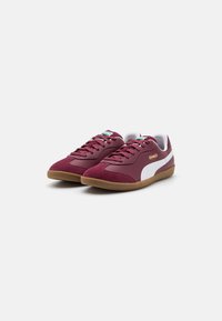 Burgundy sneakers med en texturerad ovandel, vita läderdetaljer och en sula av gummigummi. En enkel snörning med logotydlighet.