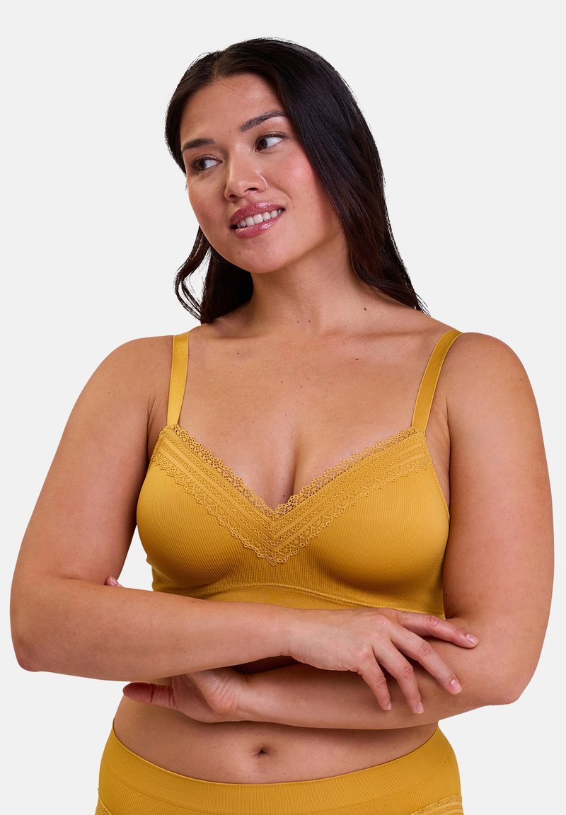 Bralette jaune moutarde avec un décolleté en V, texture côtelée, garniture en dentelle au niveau du décolleté et bretelles ajustables.