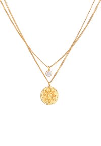 Collana a più fili in tono dorato con un pendente circolare testurizzato decorato con un design solare e una piccola pietra preziosa trasparente su una catena sottile.