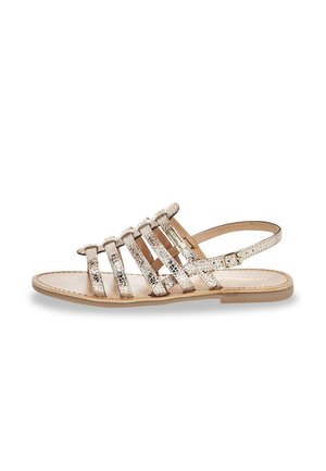Flat sandal with multiple thin, textured beige straps and a back ankle strap with buckle closure.
