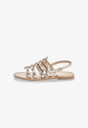 Flat sandal with multiple thin, textured beige straps and a back ankle strap with buckle closure.