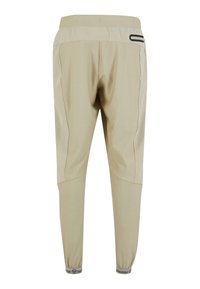 Beżowe spodnie sportowe o tapered designie, z elastycznym paskiem w talii i ściągaczami. Posiadają kontrastowe panele boczne i detal z kieszenią na zamek.