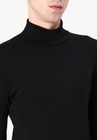 Camiseta de cuello alto negra en tejido suave, con un diseño ajustado y mangas largas, con un cuello alto que proporciona un ajuste ceñido.