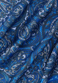 Μπλε ύφασμα με περίτεχνα σχέδια παϊέτας σε αποχρώσεις ναυτικού μπλε, λευκού και ανοιχτού μπλε, που παρουσιάζει λεπτομερή ανθικά και κυρτά μοτίβα.