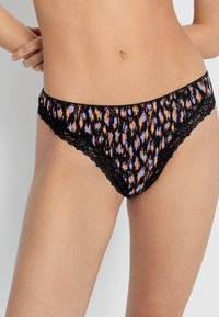 Melna apakšveļa ar mežģīņu apdari, kurai ir krāsains oranžu un violetu raksts uz tumša fona; izgatavota no mīksta auduma un ar zemu jostasvietu.