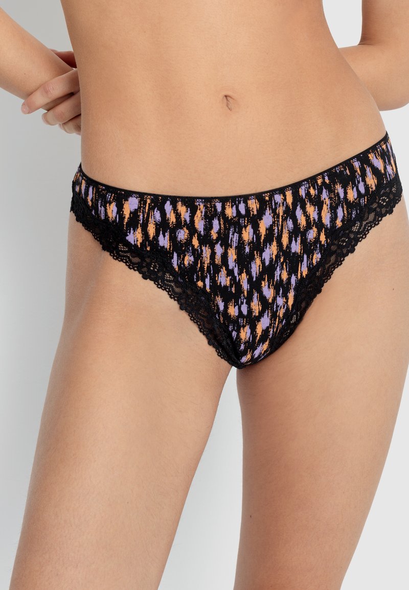 Melna apakšveļa ar mežģīņu apdari, kurai ir krāsains oranžu un violetu raksts uz tumša fona; izgatavota no mīksta auduma un ar zemu jostasvietu.