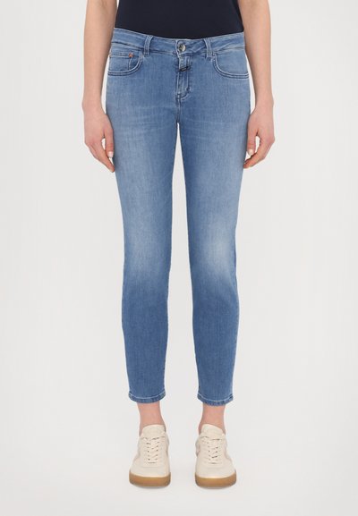 Jeans de color azul claro con corte ajustado, diseño de cinco bolsillos y un desvanecimiento mínimo. Acabados con un cierre de botón y un pequeño logotipo de la marca en la parte frontal.