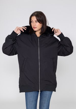 Schwarze Bomberjacke mit einem Kunstfellkragen, Reißverschluss, gerippten Bündchen und Seitentaschen. Aus glattem, leichtem Material gefertigt.