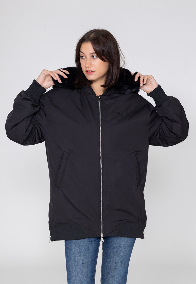 Zwart bomberjack met een faux fur kraag, ritssluiting, geribde manchetten en zijzakken. Gemaakt van glad, lichtgewicht materiaal.
