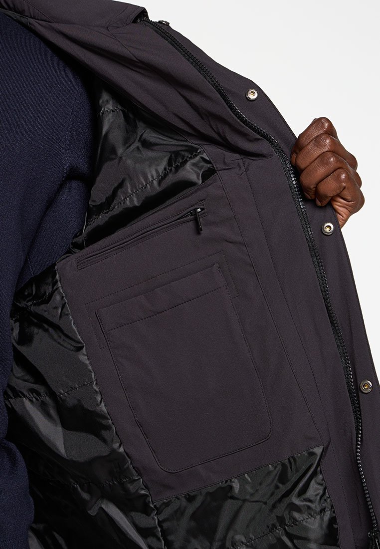 Czarna, ocieplona kurtka od wewnątrz z gładkim, błyszczącym podszewkiem. Posiada dużą kieszeń oraz mniejszą, zapinaną na zamek kieszeń do przechowywania.