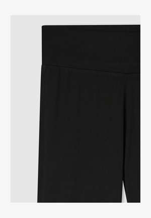 Leggings neri con una cintura ampia e elasticizzata. Realizzati in un materiale liscio e elastico, presentano un design pulito e senza cuciture.