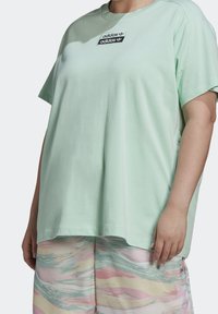 Mentolově zelené oversize tričko vyrobené z jemné bavlny. Na hrudi má černobílou nášivku s logem Adidas. Krátké rukávy, uvolněný střih.