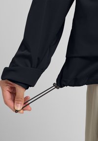 Zwarte jacksleeve met een opgerolde manchet, voorzien van een trekkoordversteller en een gladde, gestructureerde stof.