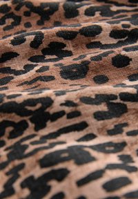 Tkanina s uzorkom leoparda u nijansama smeđe i crne boje, koja ima meku teksturu i raznolike uzorke na laganoj podlozi.