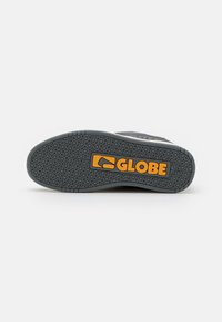 Black rubber sole with textured tread pattern, featuring an orange "GLOBE" logo in the center. Smooth surface and reinforced edges.