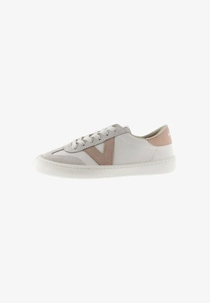 White low-top sneaker with beige suede "V" design, white laces, and beige heel tab on a white sole.