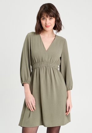 Olijfgroen jurk met een V-hals, elastische taille en driekwartlange pofmouwen. Gemaakt van lichtgewicht stof met een zachte textuur.