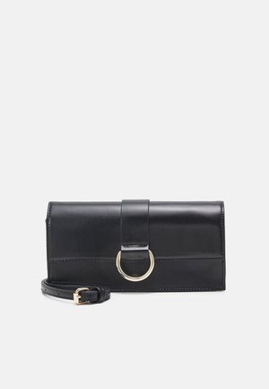 Pochette rectangulaire en cuir noir avec un détail d'anneau doré à l'avant et une bandoulière amovible et réglable avec boucle dorée.
