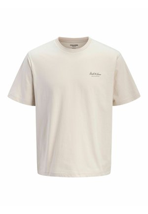 T-shirt beige à manches courtes avec col rond, avec un petit texte noir "Jack & Jones Archive Selection" sur le côté gauche de la poitrine.