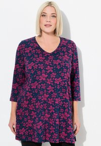 Námořnický tunik s květinovým vzorem v růžové a fialové barvě, s výstřihem do V a tříčtvrtečními rukávy, vyrobený z měkké tkaniny.
