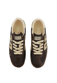 Un par de zapatillas Back 70 Streetwear en marrón oscuro y beige con cordones crema vistas desde arriba sobre un fondo blanco.