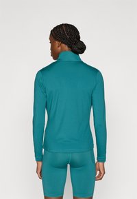 Turquoise lange mouw top met een hoge kraag, gemaakt van glad, rekbaar materiaal, gecombineerd met bijpassende strakke korte broek. Eenvoudig ontwerp, zonder zichtbare patronen.