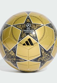 Zlatý fotbalový míč s černými hvězdnými vzory a logem UEFA Champions League. Hladký, lesklý povrch s černými akcenty a šicími detaily.