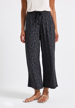 Pantaloni a gamba larga neri con motivo, vita regolabile con cordoncino e design testurizzato. Abbinati a sandali piatti beige.