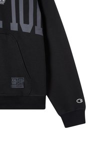 Sudadera negra con diseño gráfico en gris que incluye el texto "101", bolsillos tipo canguro, puños de canalé y logotipo bordado en la manga. Tamaño XXL visible.