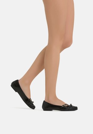 Ballerine in pelle verniciata nera con tacco piatto, caratterizzate da un dettaglio a fiocco e piccoli accenti in metallo sulla parte superiore.