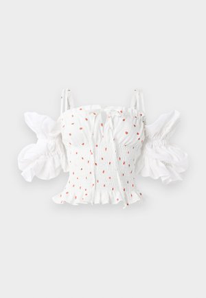 Hvit smokkertopp med små røde blomstertrykk, justerbare spaghetti-stropper og puffede ermer med volangkant.