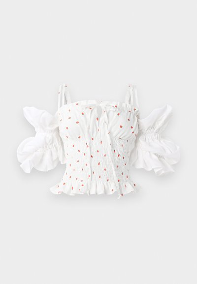 Hvid smocked top med små røde blomsterprint, justerbare spaghetti-stropper og puffede ærmer med en flæset kant.