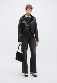 Fekete bőr rövidített dzseki műszőrme gallérral, sötétszürke, bővülő fazonú farmerral és hegyes orrú fekete magassarkúval párosítva. Tartozik hozzá egy fekete kézitáska is.