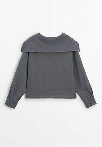 Haut à rayures gris à manches longues, avec un design décolleté et des poignets boutonnés. Fabriqué dans un tissu texturé avec une forme carrée.