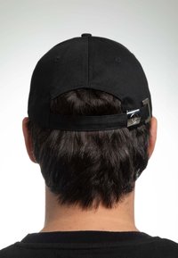 Cappellino da baseball nero con visiera piatta, striscia regolabile e dettaglio metallico sul retro, visto da dietro con capelli corti visibili.