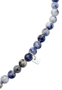 Bracelet en perles avec des pierres rondes bleues et grises parsemées de speckles noires, agrémenté d'une étiquette en argent attachée à une boucle en métal.
