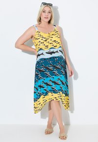 Vestido sin mangas con una parte superior amarilla con estampado de peces, que transiciona a una parte inferior azul con diseños de tiburones, tela suave.