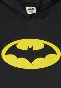 Sudadera negra con capucha que presenta un gran logo de Batman en amarillo centrado en la parte frontal. El material es de algodón, con una textura suave y un diseño clásico.