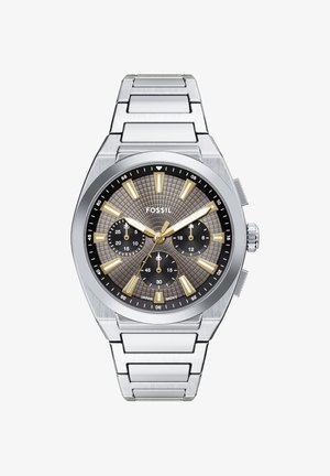 Fossil ur i rustfrit stål med grå tekstureret urskive, guldfarvede timeindikatorer og visere, tre sorte delskiver og metalarmbånd.
