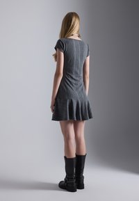 Robe ajustée gris foncé, à manches courtes et à ourlet évasé. Texture côtelée, longueur genou. Bottes noires montant jusqu'aux genoux avec des accents de boucle.