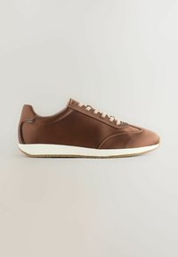 Bruna sneakers med en slät tygöverdel, kontrasterande ljusa snörningar, vit mellansula och minimalistisk design. Gummisula med greppmönster.