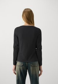 Must mustaelise varrukatega topp, ümmarguse kaelusega, pehmest kangast. Kantakse heledate siniste pesuehituspükste koos fades gradient ja tagakotiga.