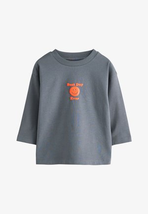 Grå langærmet skjorte med ribbet krave og orange tekst med teksten "Best Day Ever" over og under et smilende ansigt på brystet.