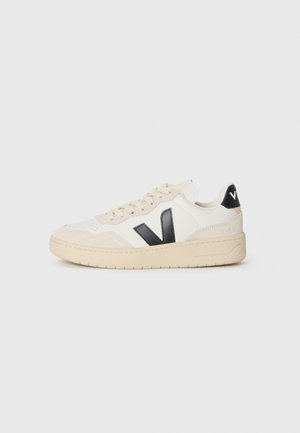 Sneaker v off-white farbe s béžovou podrážkou, čiernym logom "V" na boku, šnúrkami a čiernym pätkom so značkou v bielych písmenách.