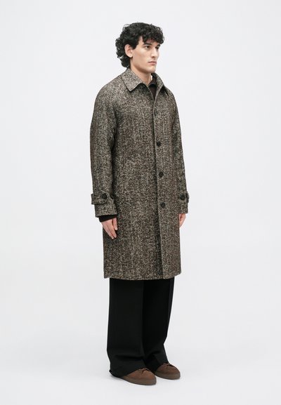 Pruun houndstooth-kattega peacoat, millel on struktureeritud krae, nööbid ja küljetaskud. Kandmine mustade pükste ja pruunide kingade üle.