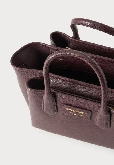 Sac à main en cuir texturé marron foncé avec deux anses et un logo doré Emporio Armani Milano 1981 à l'avant.