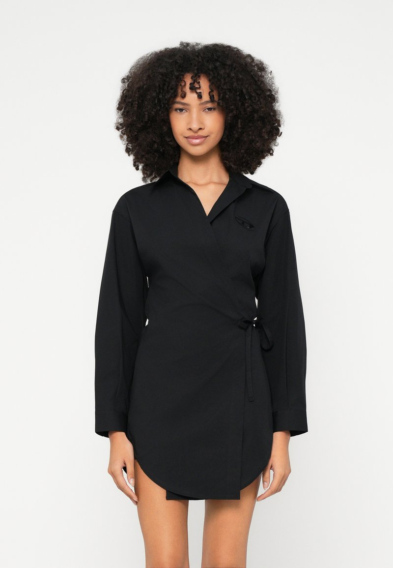 Čierne zavinovacie šaty s golierovým výstrihom, dlhými rukávmi a viazaním na boku. Hladká textúra a detail zaobleného okraja. Minimalistický dizajn.