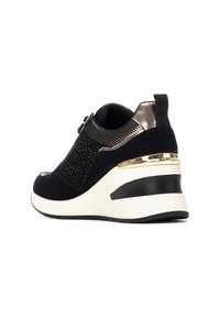 Zapatilla deportiva negra con tacón cuña, materiales de ante y malla, acentos metálicos y diseño texturizado en la parte superior.