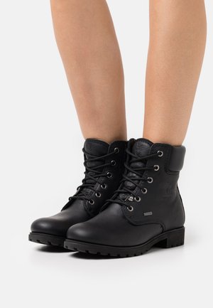 Bottines en cuir noir avec bout rond, laçage à l'avant, col rembourré, finition texturée et semelle robuste. Accents en métal inclus.