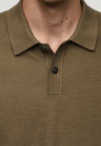 Tummanvihre ä polo-paita, joka on valmistettu teksturoidusta kankaasta. Paidassa on kaulus, kolme napinläpeä ja slim fit -malli.